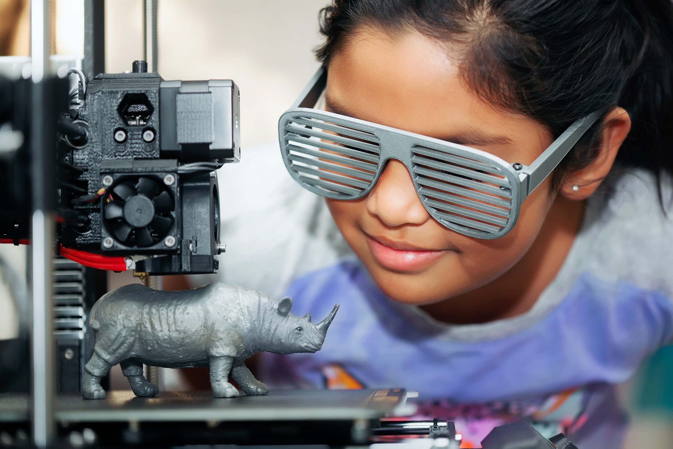 Cute Girl With Cool D Printed Shutter Shades Is Watching Her D Printer As It Prints Her D Model Of A Rhinoceros